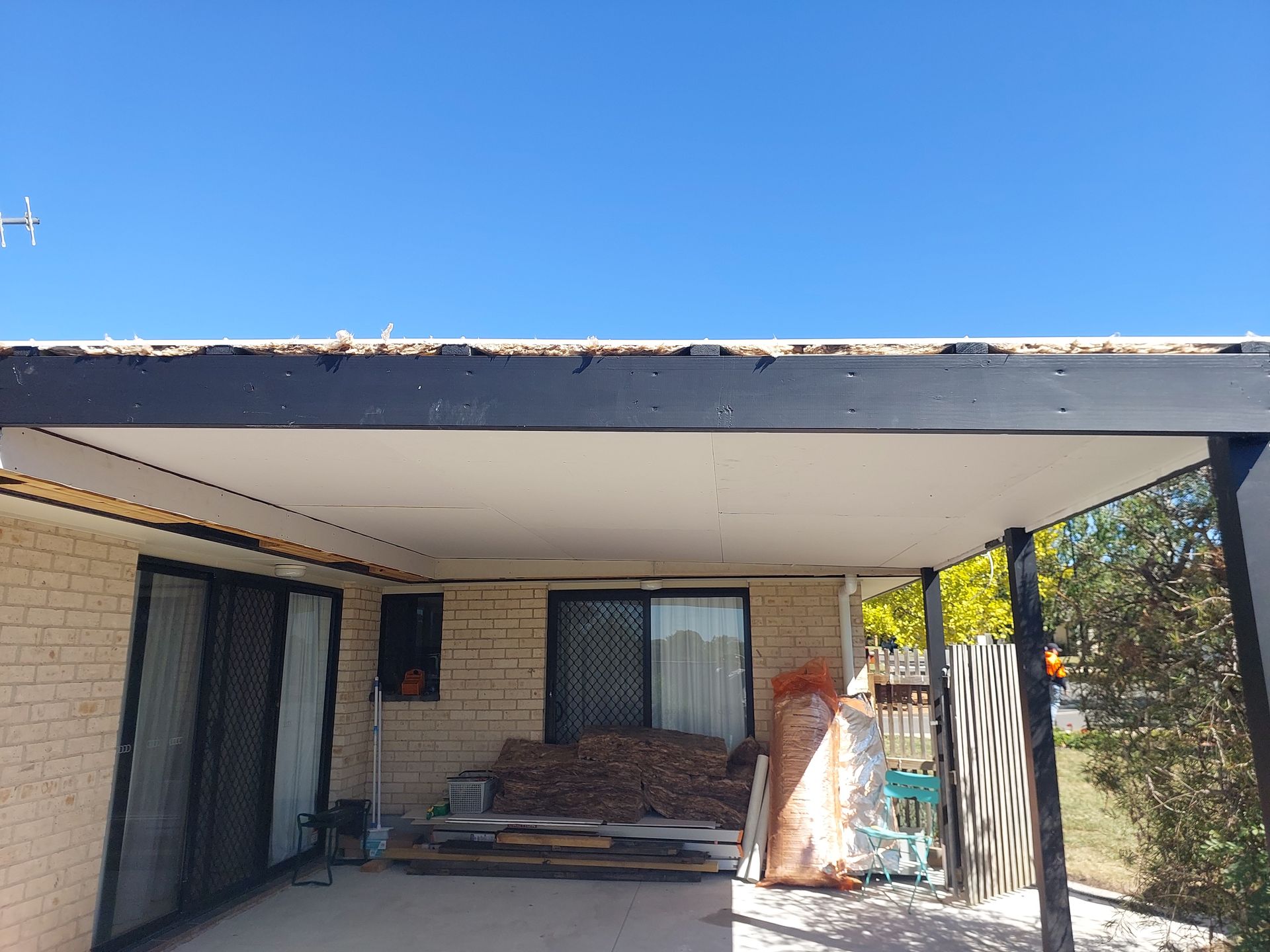 a Covered Patio With a White Ceiling and Black Beams, Attached to a Brick House — Elimar Construction in Goulburn, NSW