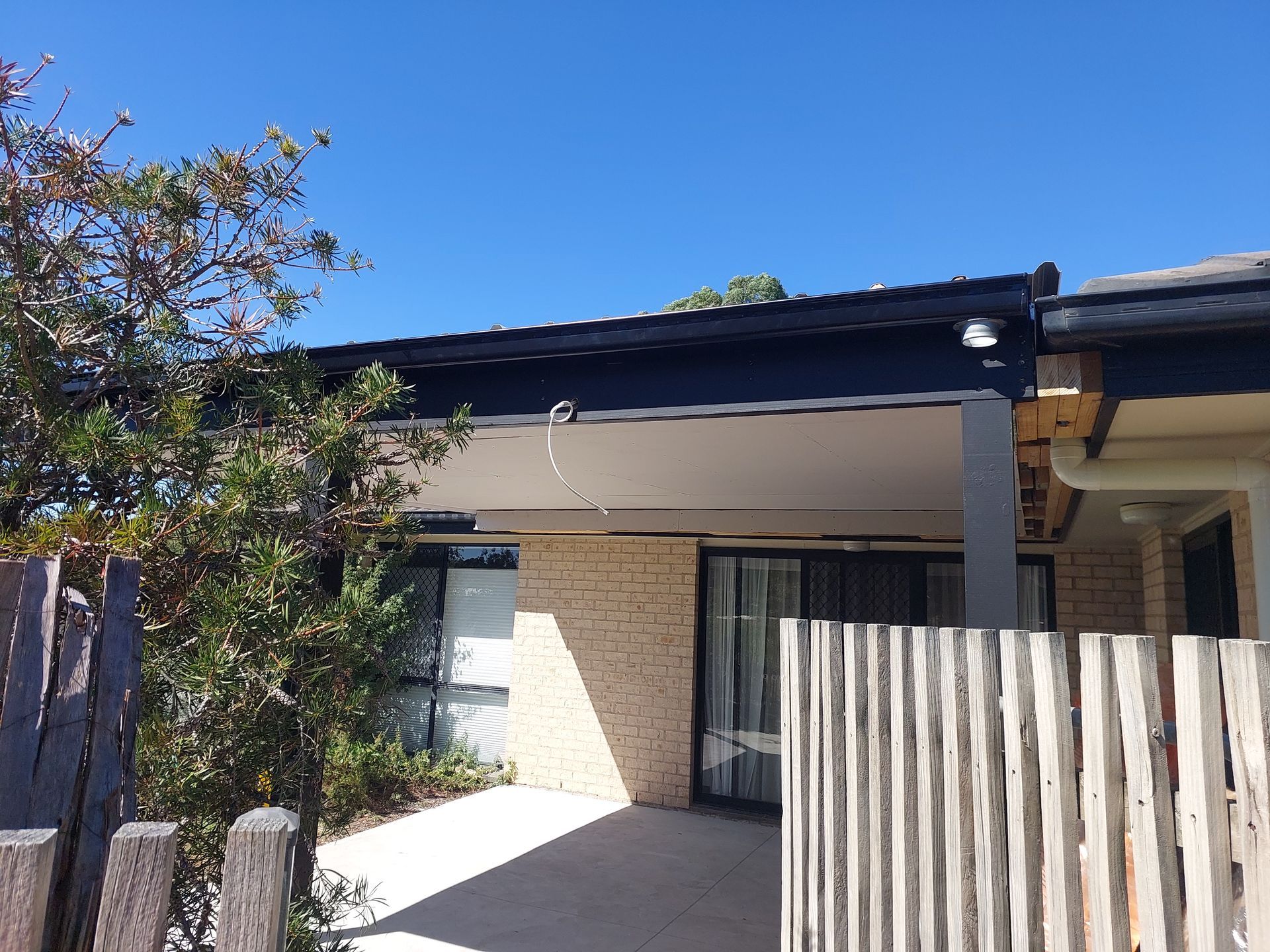 Tan Brick Building With a Covered Patio, a Wooden Fence, and a Clear Blue Sky — Elimar Construction in Goulburn, NSW