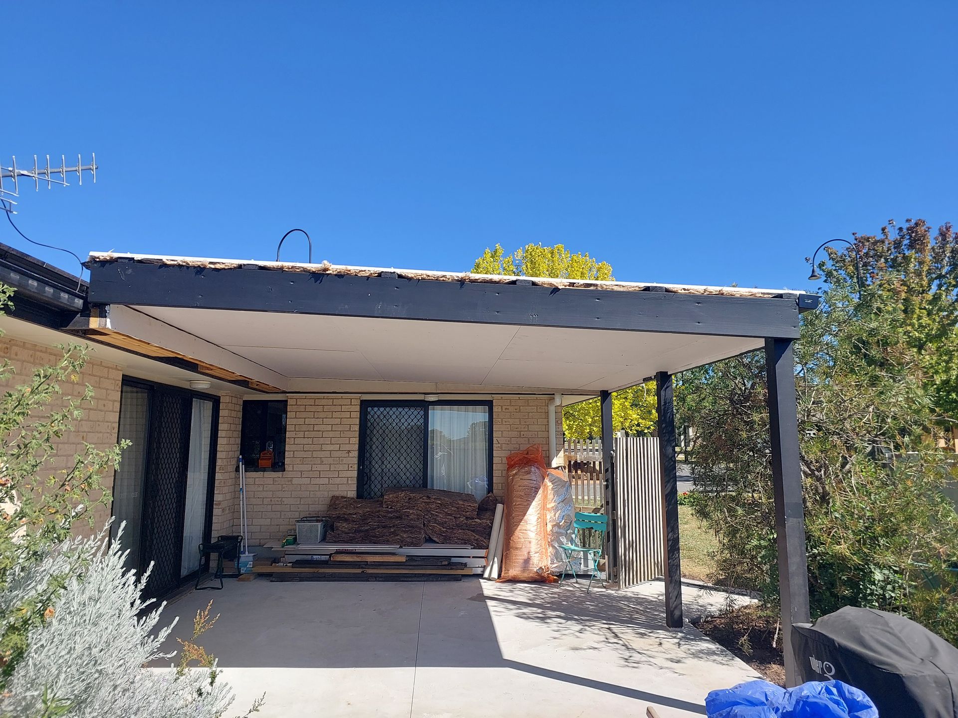 Patio With a Black-framed Roof, a Brick Wall, and a Clear Blue Sky — Elimar Construction in Goulburn, NSW