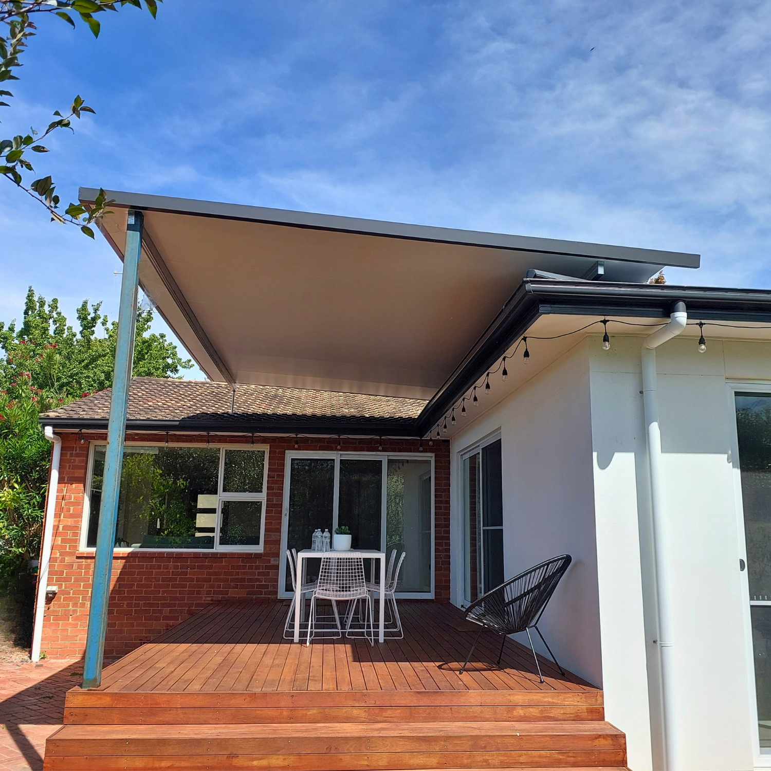 A Deck With a Beige Awning and Outdoor Furniture — Elimar Construction in Goulburn, NSW