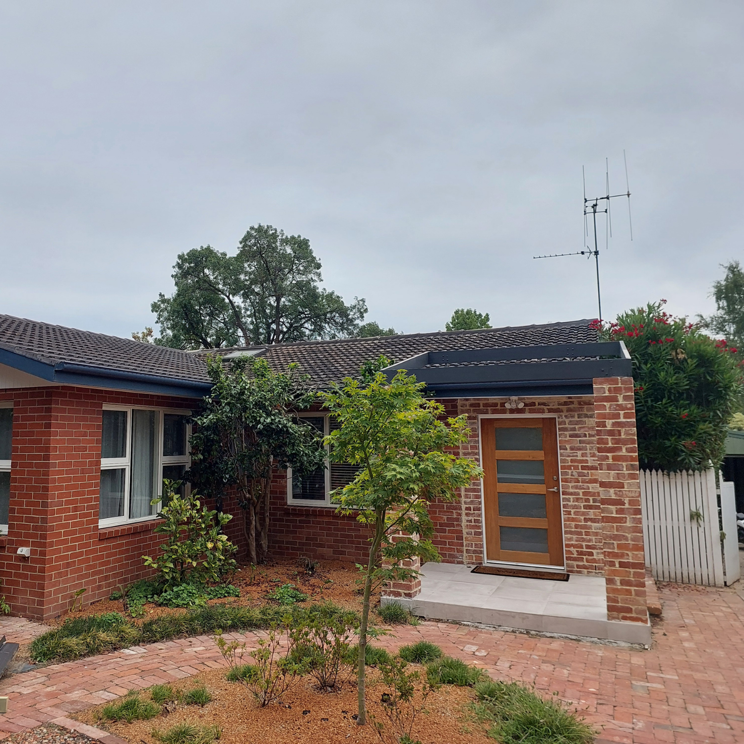 Brick House With Brown Door, Red Brick Path and Small Garden — Elimar Construction in Goulburn, NSW