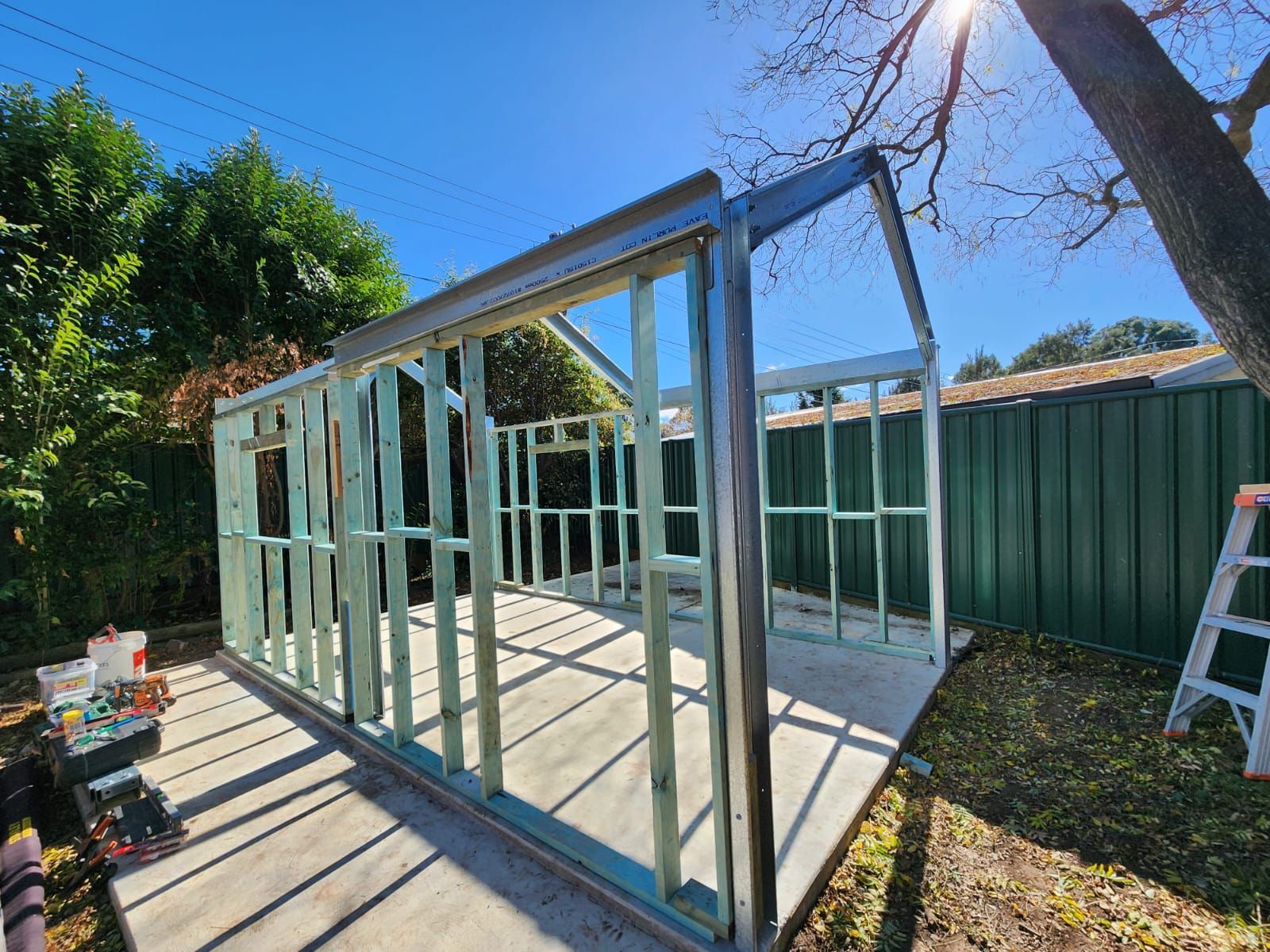 a Shed Under Construction With Wooden Studs and Metal Framing on a Concrete Base, Backyard Setting — Elimar Construction in Goulburn, NSW