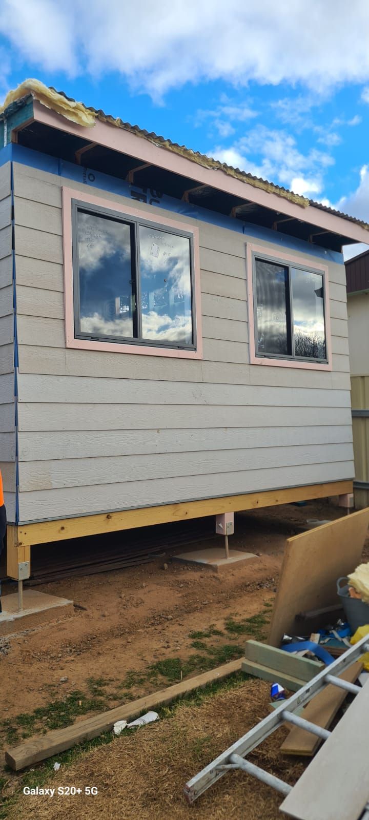 a Small Building Under Construction, With Horizontal Siding, Two Windows, and a Partially Finished Roof, Set Against a Cloudy Sky — Elimar Construction in Goulburn, NSW