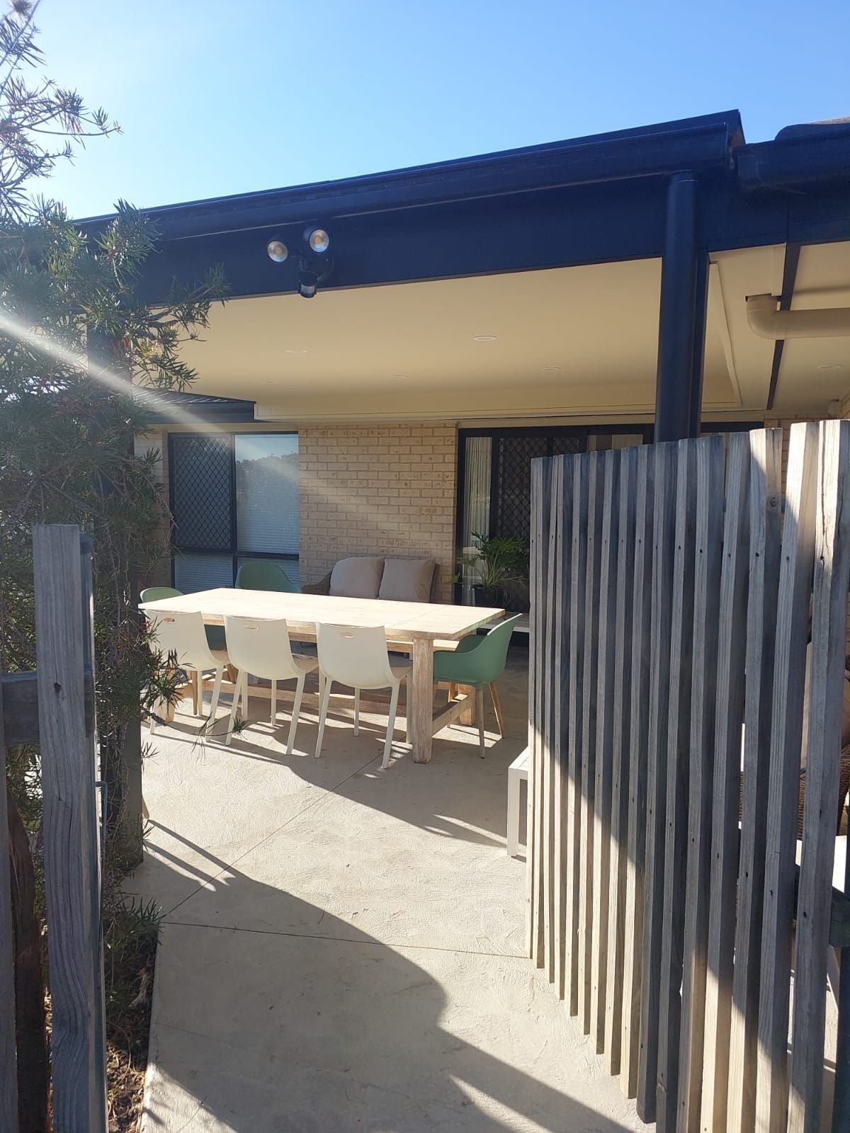 Outdoor Patio With Dining Table, Chairs, and Couch Under a Roof. Wooden Fence on Right — Elimar Construction in Goulburn, NSW