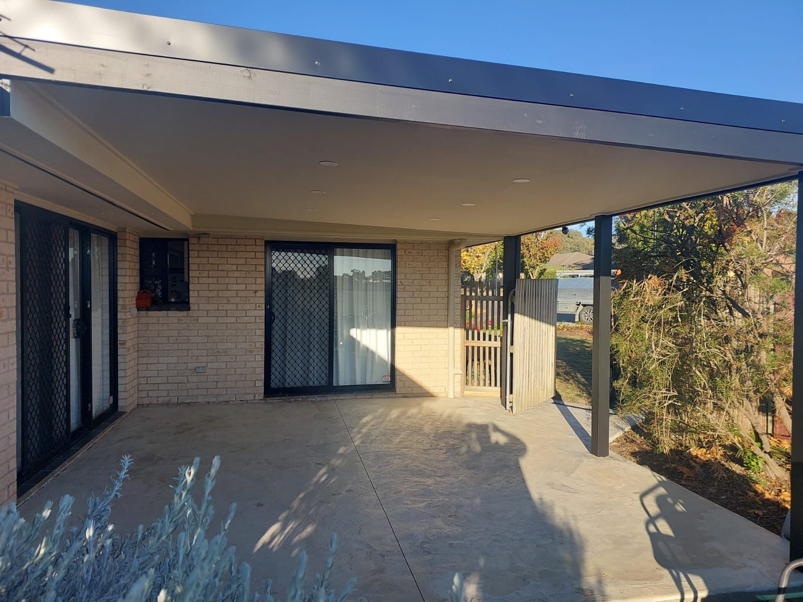 Patio With Gray Roof, Concrete Floor, Brick Wall, and a Sliding Glass Door — Elimar Construction in Goulburn, NSW