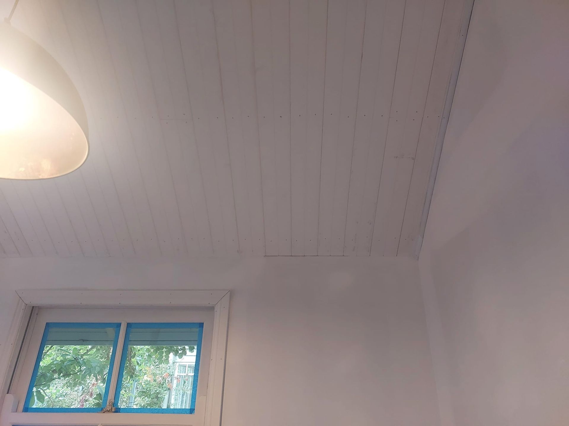White-painted Wooden Plank Ceiling With a Light Fixture and Window With Green View — Elimar Construction in Goulburn, NSW