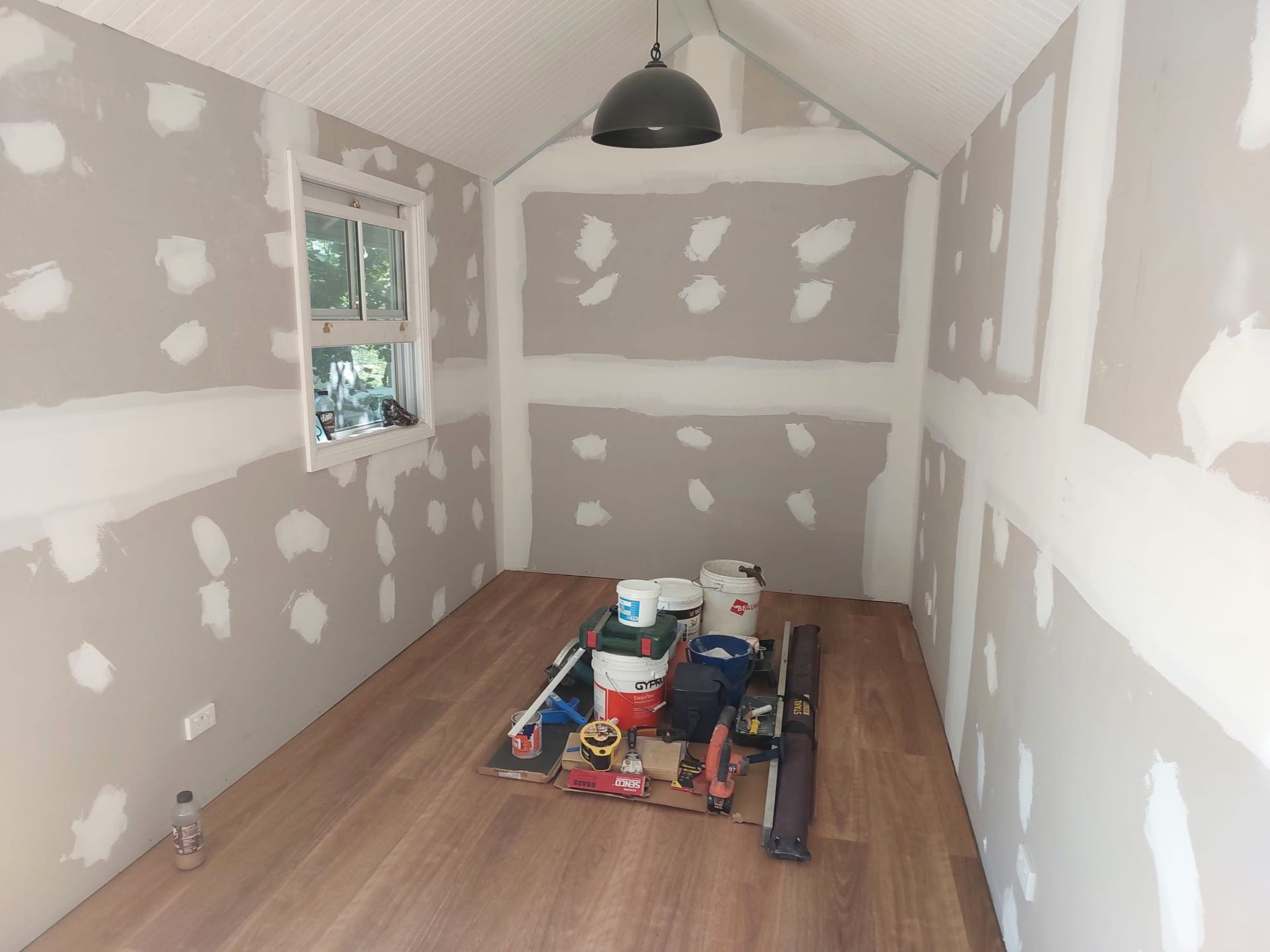 Interior of a Small Room Under Construction With Wood Flooring, Drywall, and Tools  — Elimar Construction in Goulburn, NSW