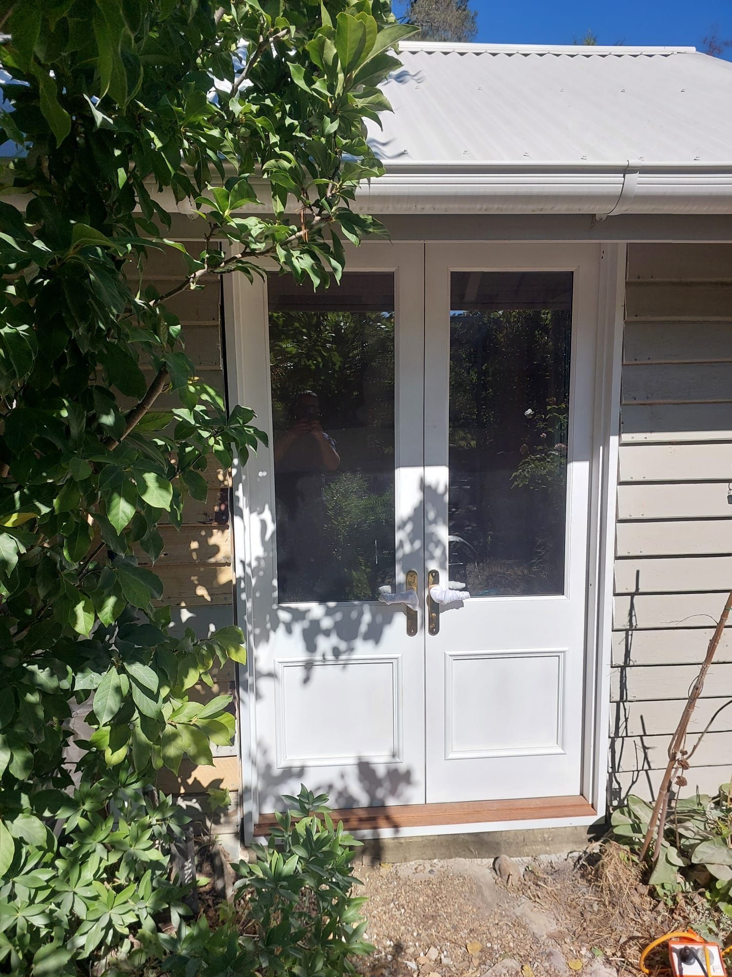 White Double Doors With Glass Panels, Set in a Light-colored Building, Surrounded by Greenery — Elimar Construction in Goulburn, NSW