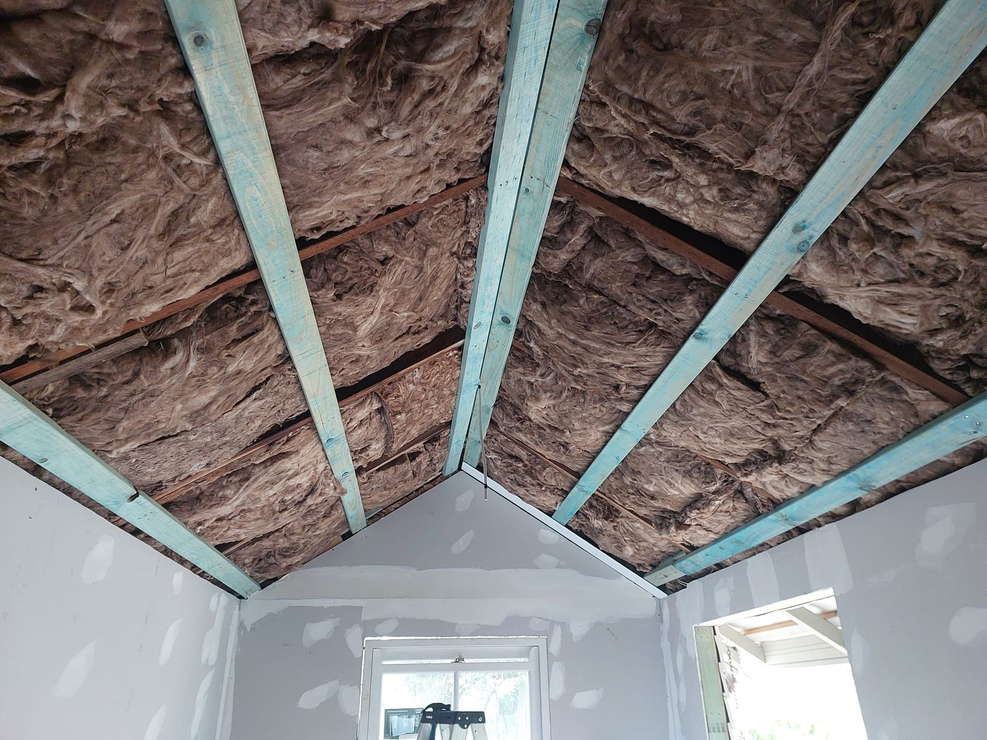 Interior View of a Room With Exposed Rafters and Insulation, Drywall on Walls, and a Window — Elimar Construction in Goulburn, NSW
