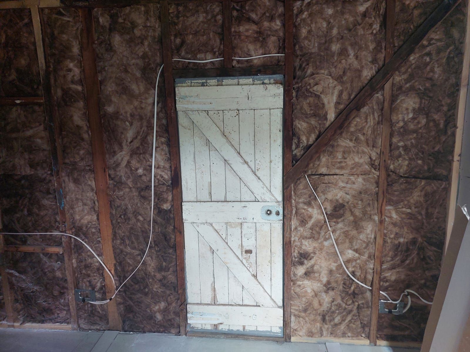 Interior Wall Under Construction With Insulation, Door. Wires, Wooden Frame, and Aged White Door — Elimar Construction in Goulburn, NSW