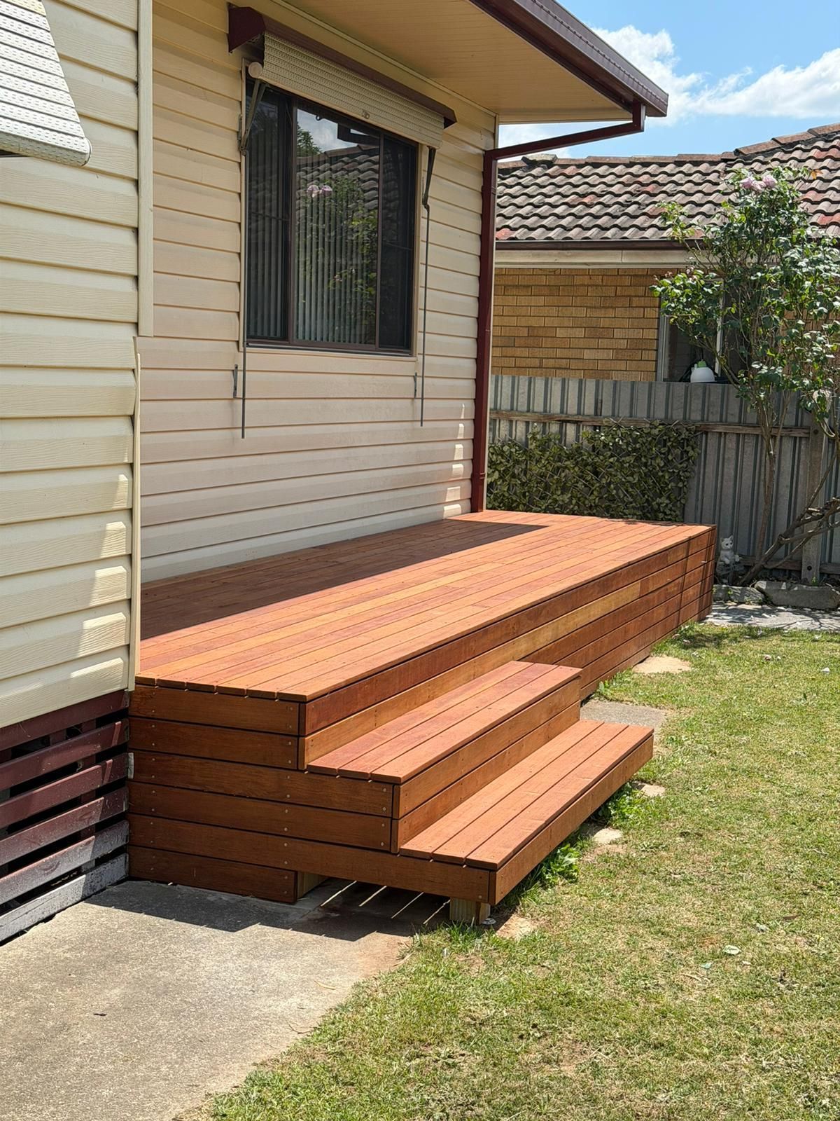 Wooden deck steps beside a beige house, next to a grassy yard and fence — Elimar Construction in Goulburn, NSW