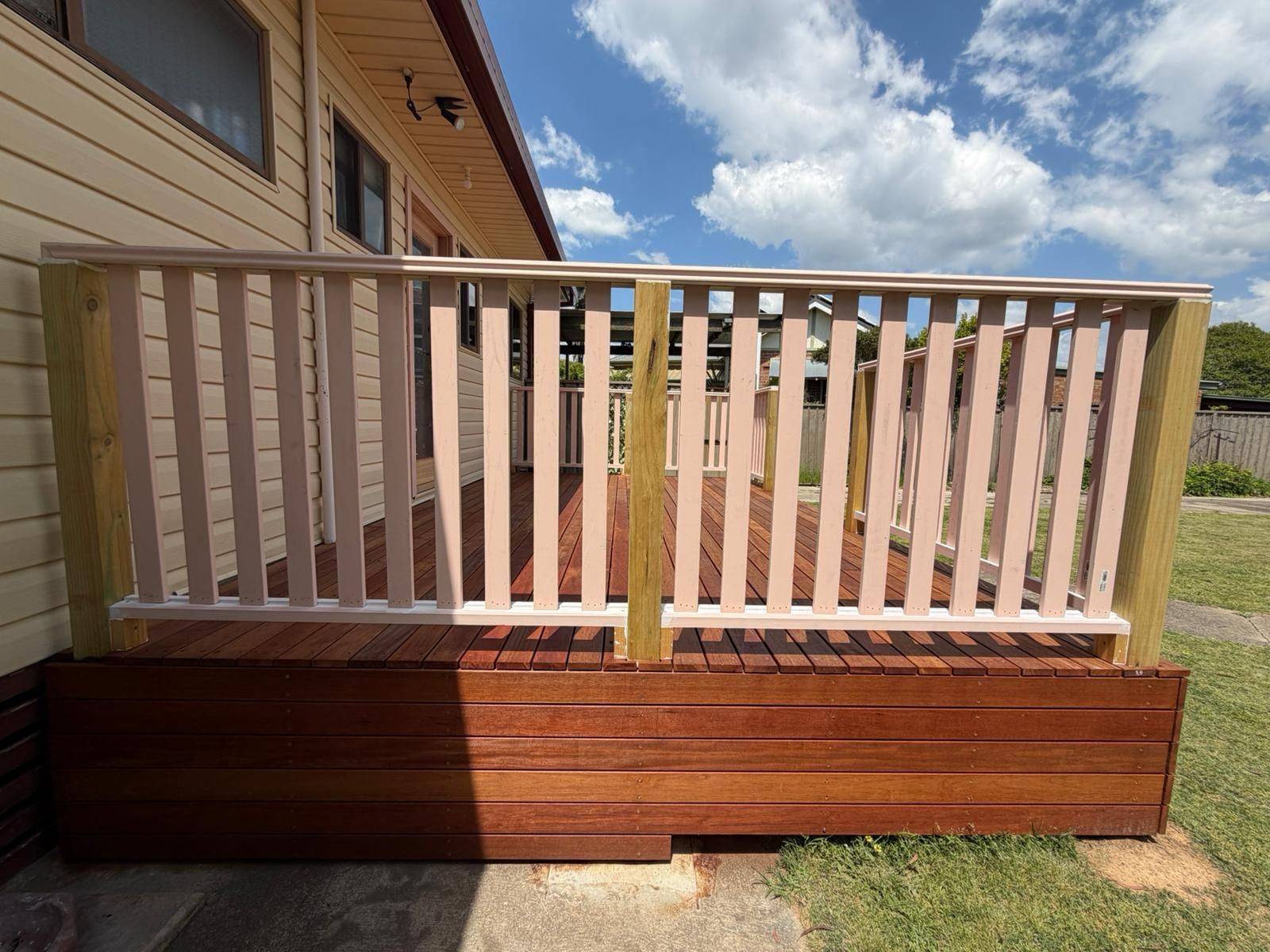 Wooden deck ramp with white railings beside a house on a sunny day — Elimar Construction in Goulburn, NSW