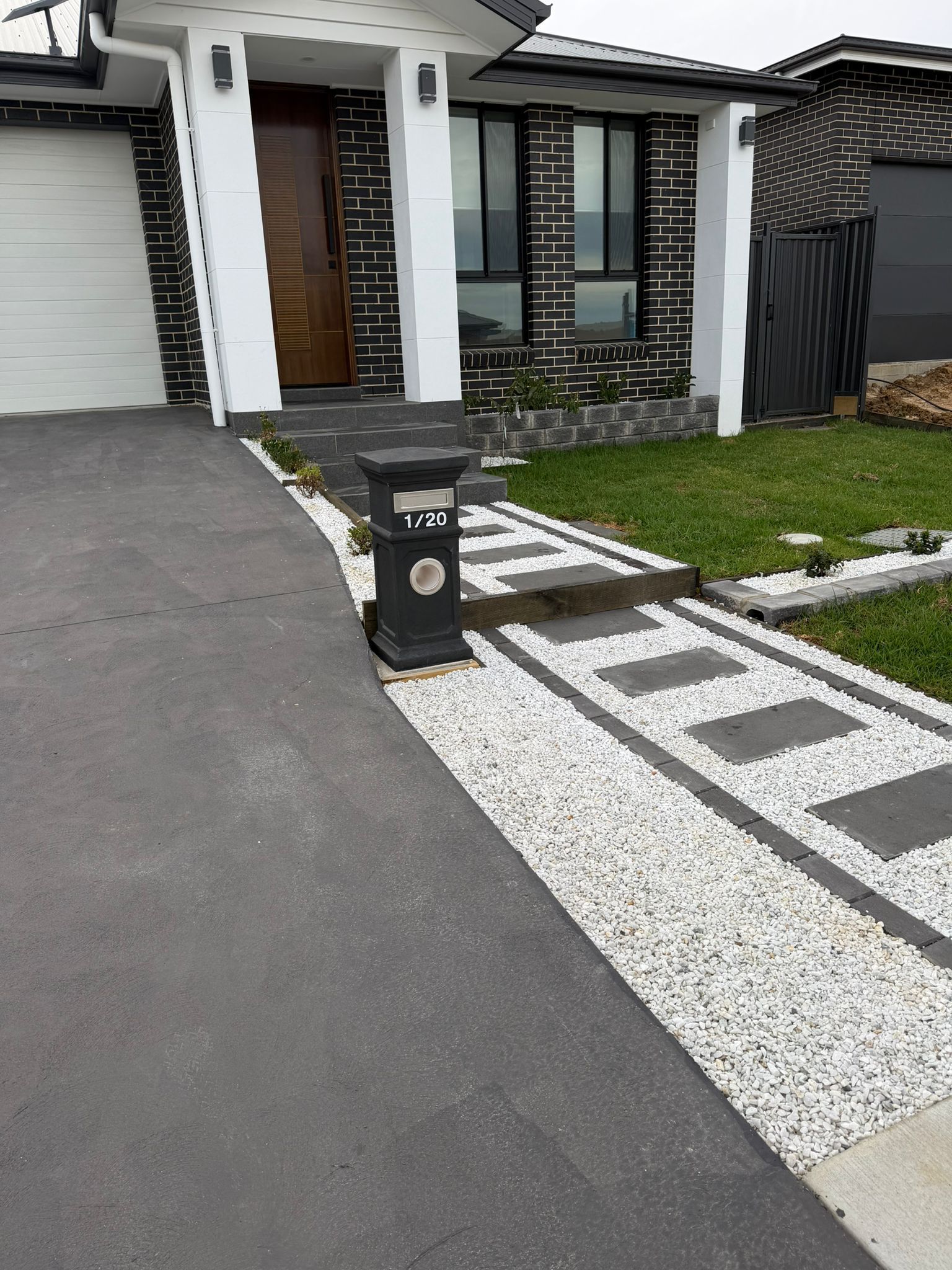 Modern house entrance with driveway, black gate, and small landscaped front yard — Elimar Construction in Goulburn, NSW