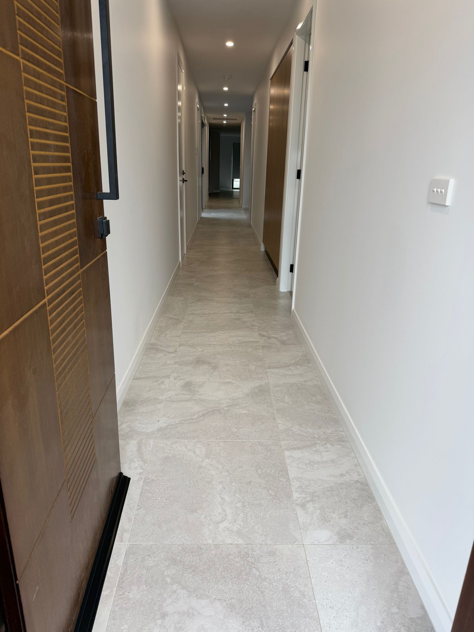 Narrow hallway with white walls, beige tile floor, and a wooden door on the left — Elimar Construction in Goulburn, NSW