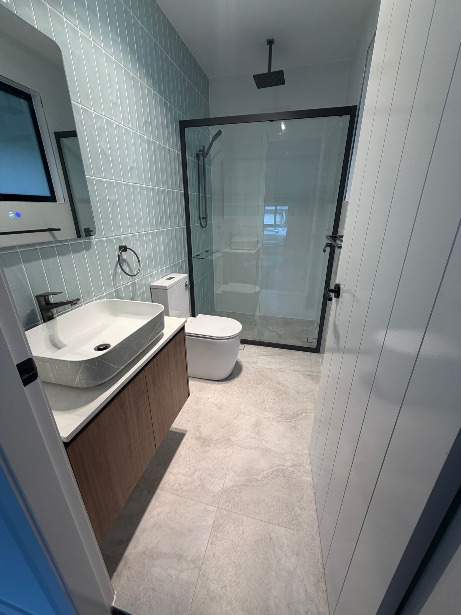 Modern bathroom with vanity sink, toilet, and glass walk-in shower in light gray tones — Elimar Construction in Goulburn, NSW