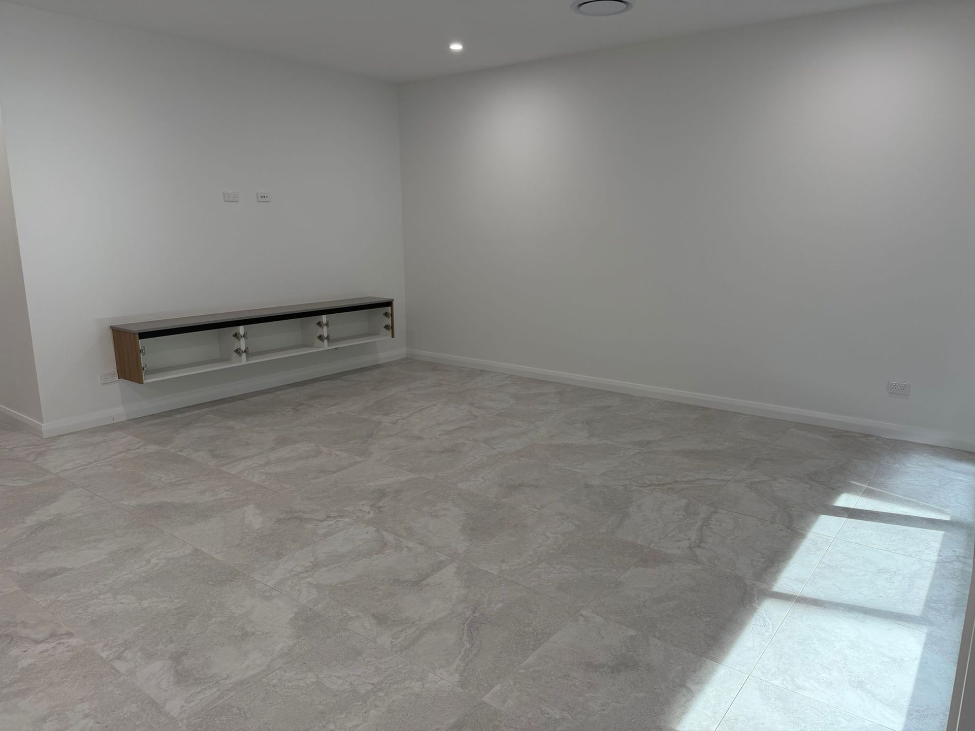 Empty white living room with gray carpet and built-in bench along one wall — Elimar Construction in Goulburn, NSW