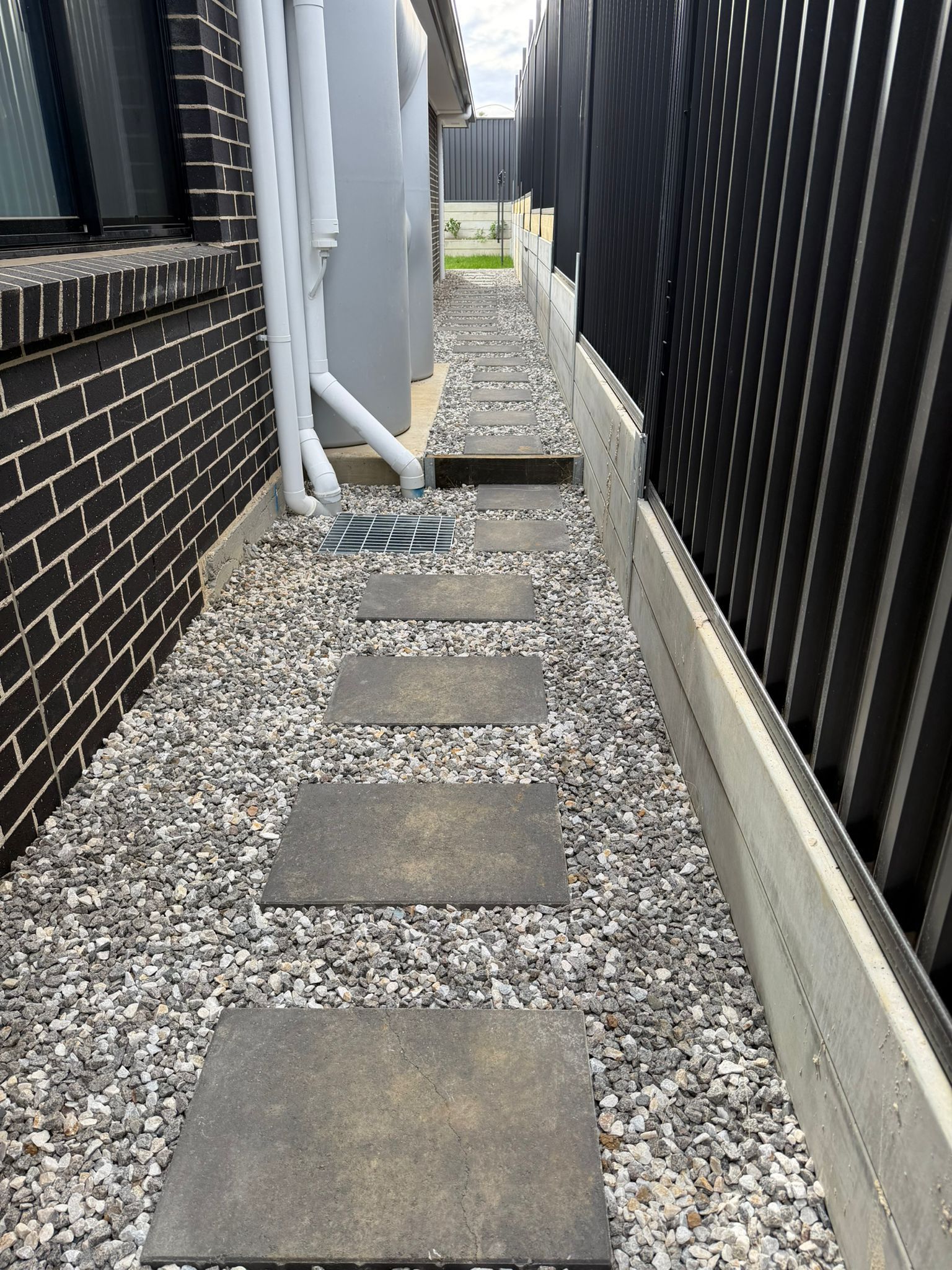 Narrow gravel pathway with stepping stones between two houses, leading to a backyard gate — Elimar Construction in Goulburn, NSW