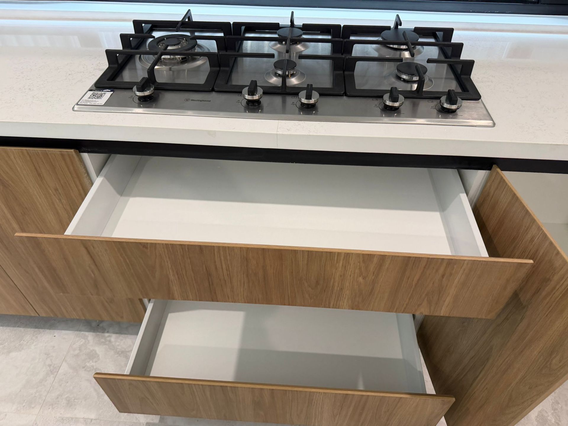 Kitchen drawer under a gas cooktop with two empty pull-out drawers, one open — Elimar Construction in Goulburn, NSW