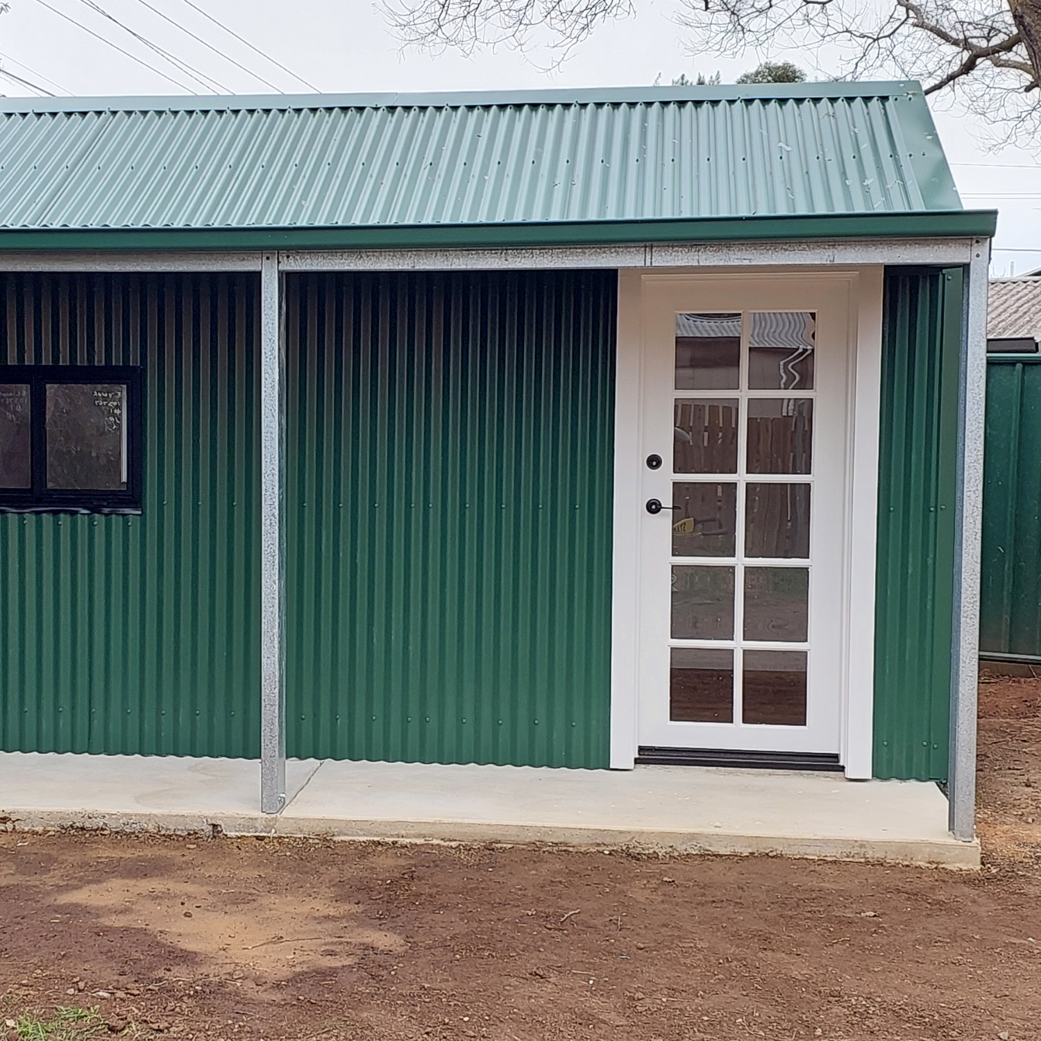 Green Corrugated Iron Shed With White Door, Black-framed Window — Elimar Construction in Goulburn, NSW