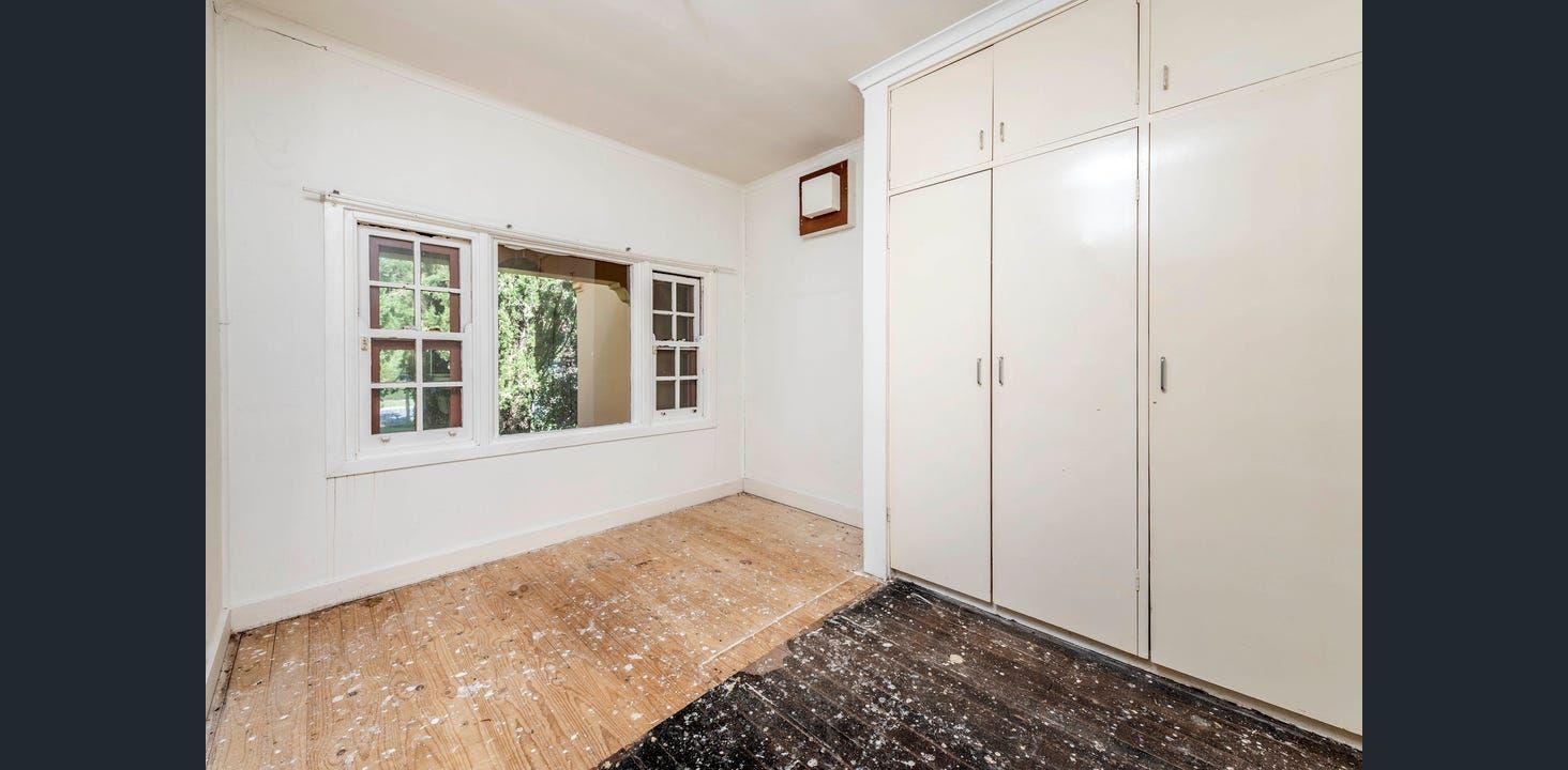 Bright Room With a Large Window and Built-in White Cabinets. Wooden Floor and a Dark Rug Are Present  — Elimar Construction in Goulburn, NSW