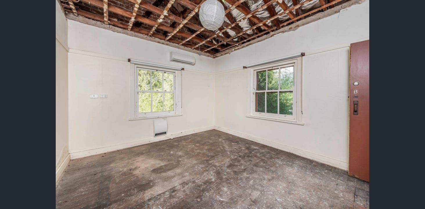 Empty Room With Unfinished Ceiling, Two Windows, and Stained Floor. Brown Door on the Right  — Elimar Construction in Goulburn, NSW