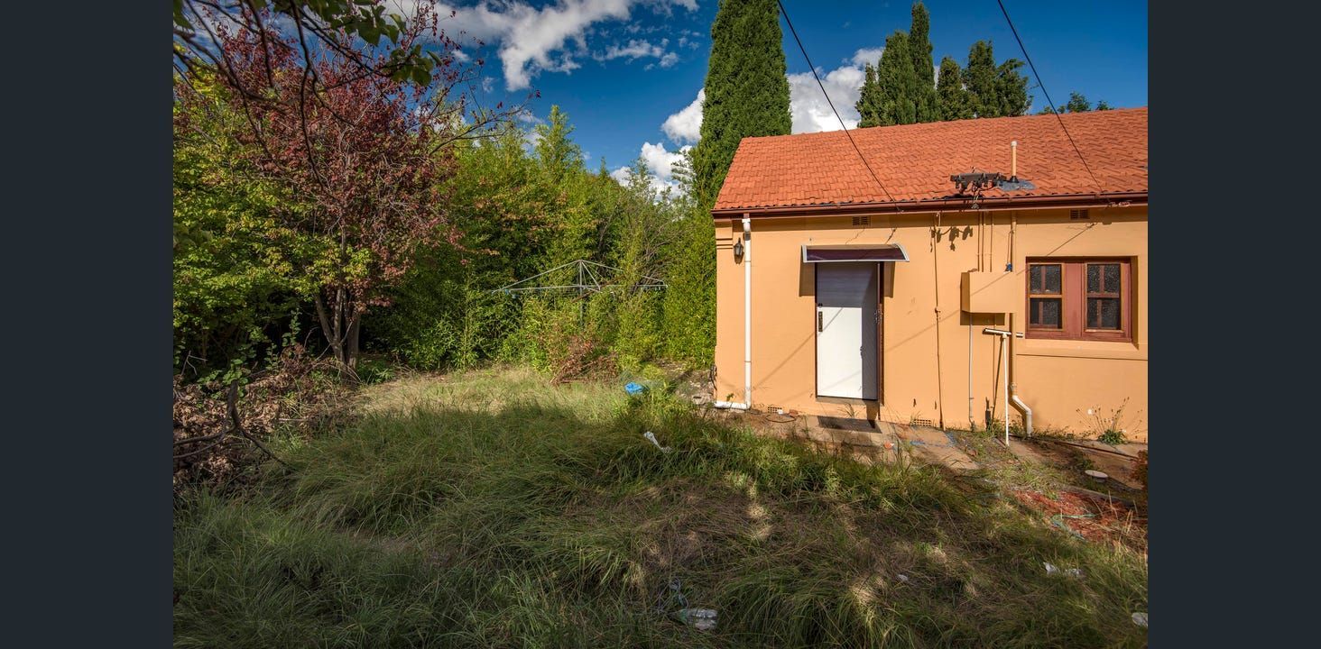 Small, Orange Building With Red Tile Roof, Surrounded by Trees and Overgrown Grass, Under a Blue Sky  — Elimar Construction in Goulburn, NSW