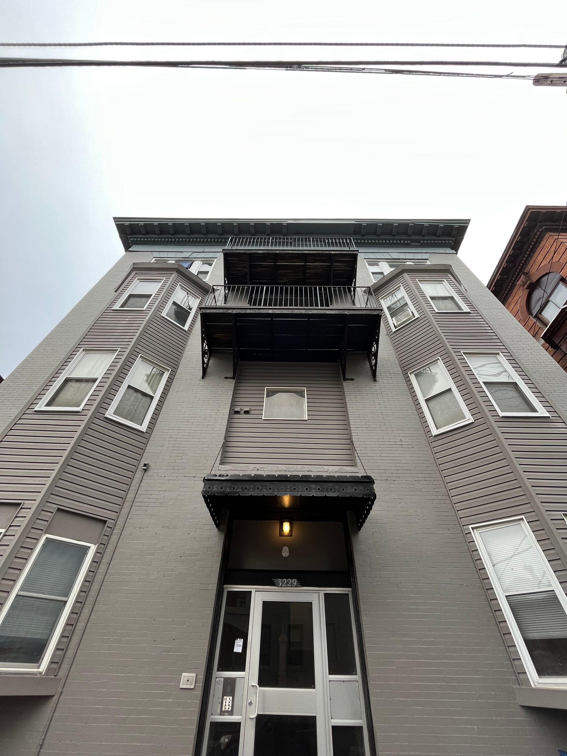 Gray building with boarded-up windows, covered porch, and a dark, overcast sky.