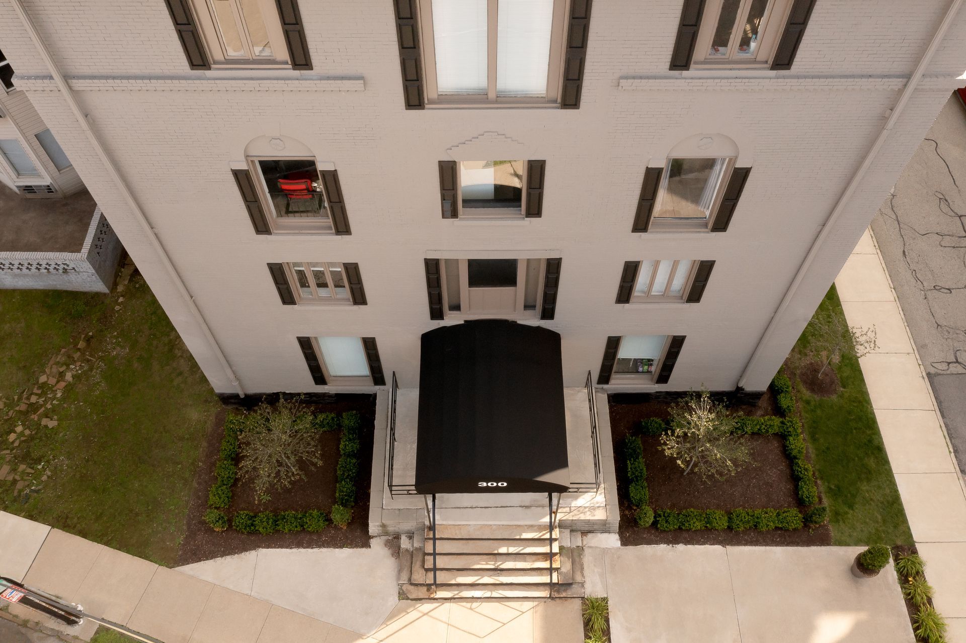 Multi-story white building with black awning, entrance, and windows.