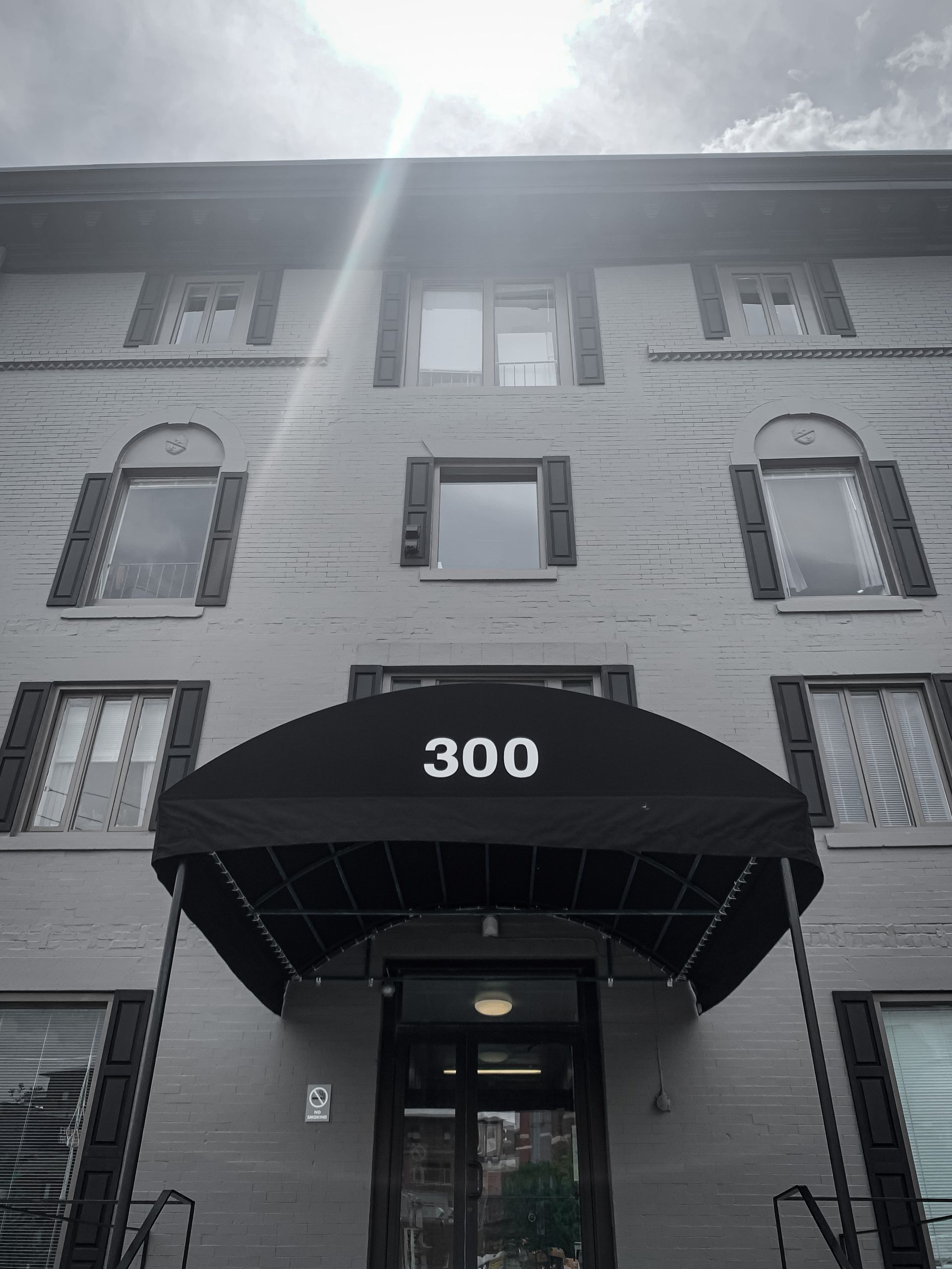Three-story building entrance with black awning; 