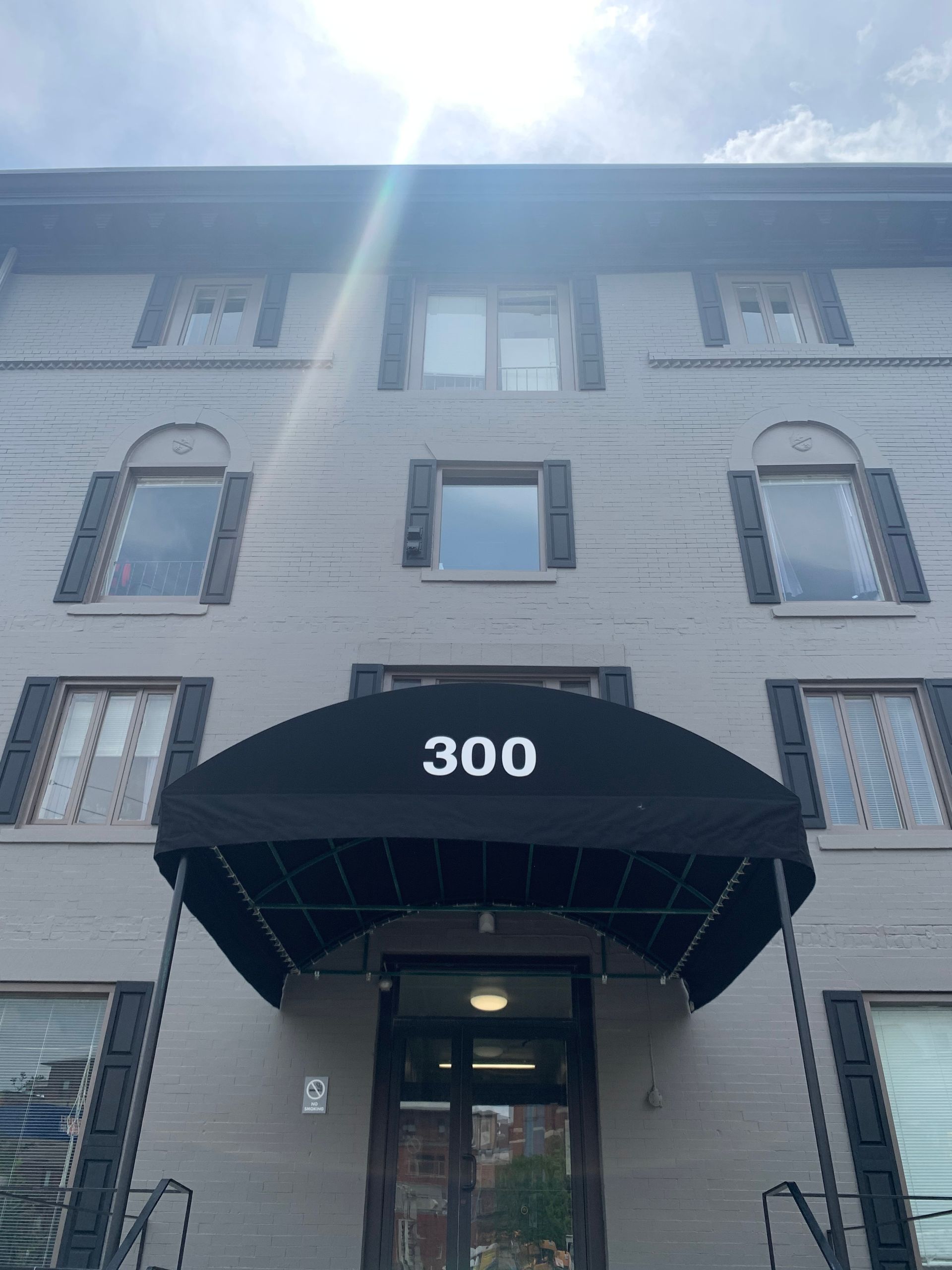 Gray building with black awning over the entrance, the number 300 is displayed.