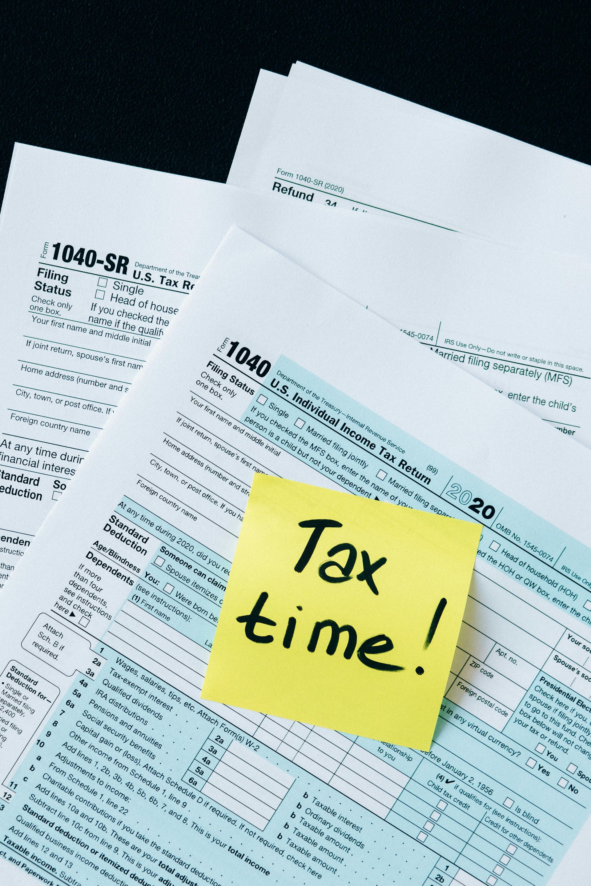 Tax forms with a yellow sticky note that says 