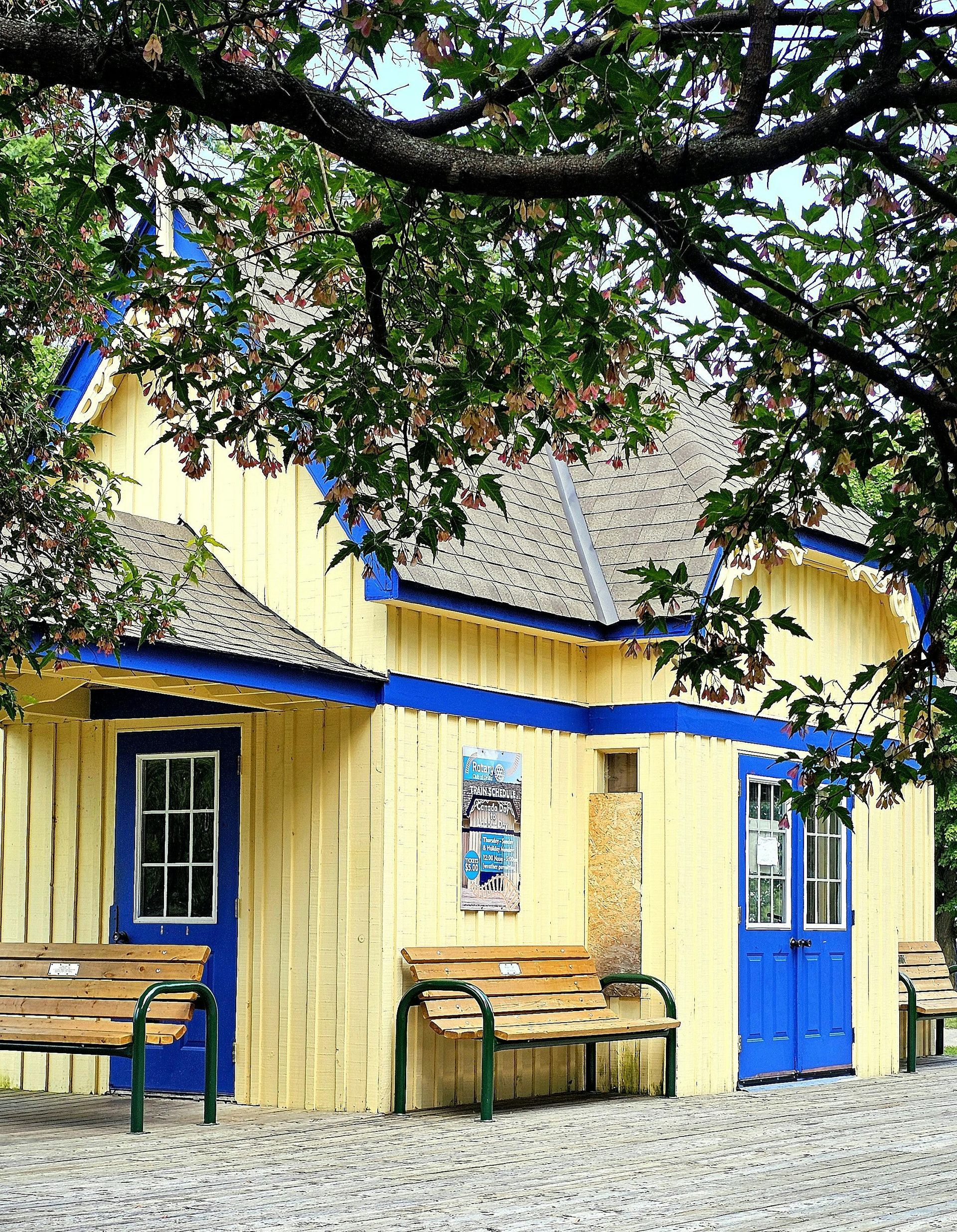 A yellow house with blue doors and a bench in front of it