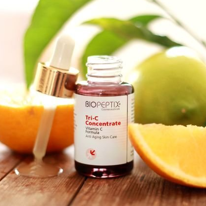 A bottle of biopeptide tri-c concentrate sits on a wooden table