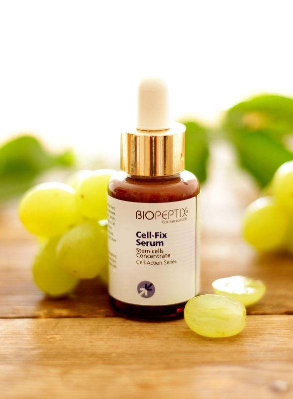 A bottle of biopeptides cell fix serum with grapes in the background