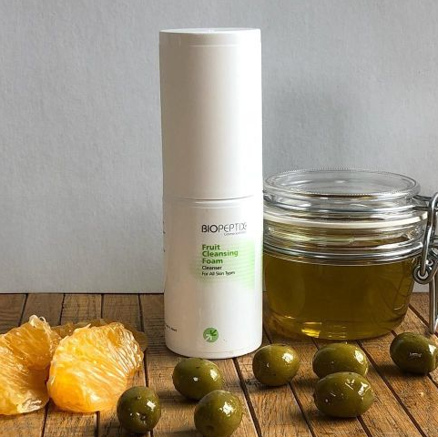 A bottle of biopoint face cleansing foam next to a jar of olive oil