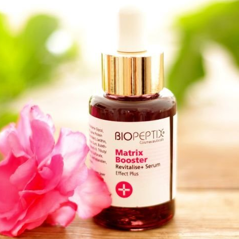 A bottle of biopepnix matrix booster next to a pink flower