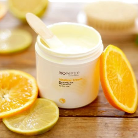 A jar of biopeptide vitamin cream surrounded by oranges and lemons