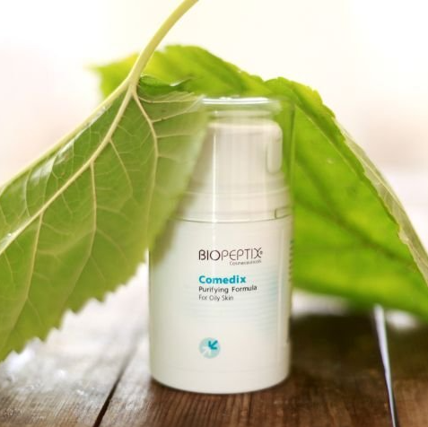 A bottle of biopeptide comedix is sitting on a wooden table