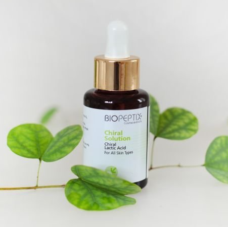 A bottle of biopeptide chiral solution is surrounded by green leaves