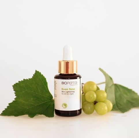 A bottle of bioneptix next to a bunch of grapes