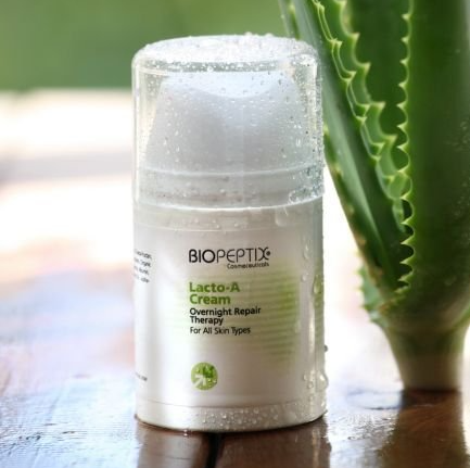A bottle of biopeptix lacto-a cream sits on a wooden table