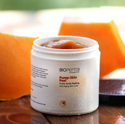A jar of biopeptide pump skin peel sits on a wooden table