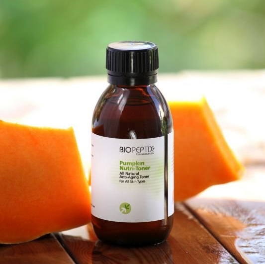 A bottle of pumpkin syrup sits on a wooden table