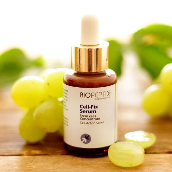 A bottle of biopeptide cell-fix serum sits on a wooden table