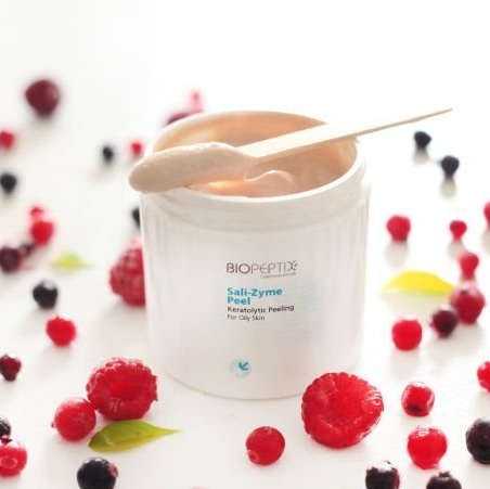 A jar of biopeptide surrounded by raspberries and blackberries