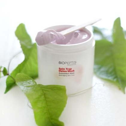 A jar of biopeptides spin trap detox mask with a spoon in it