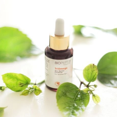 A bottle of biopeptide trioomega skin serum surrounded by green leaves