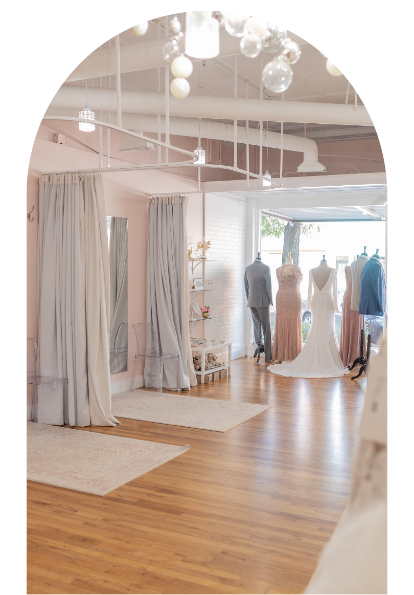 Bright boutique interior with wooden floors, hanging dresses, and soft white decor