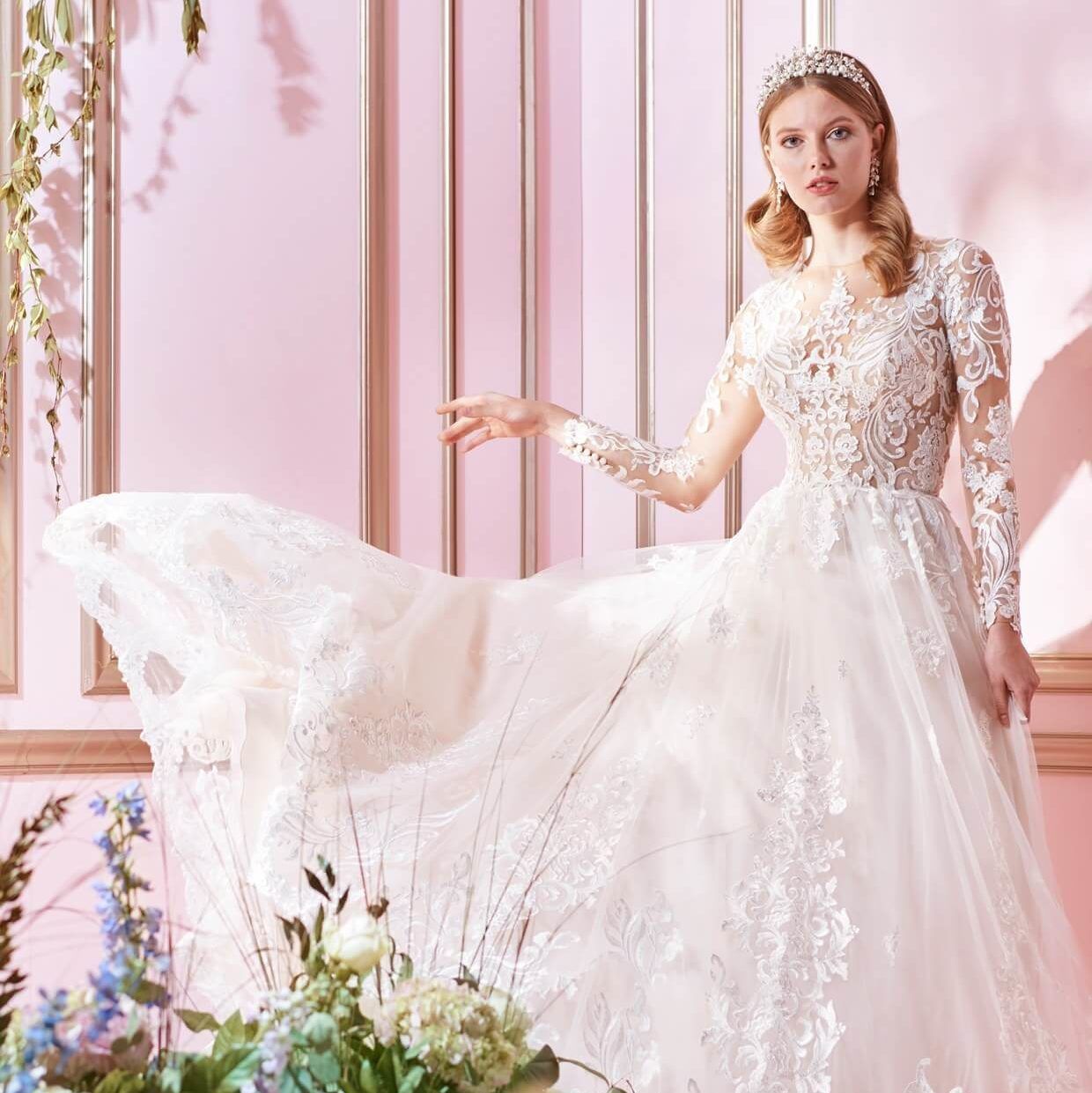 Bride in a white lace gown posing in a pink floral room