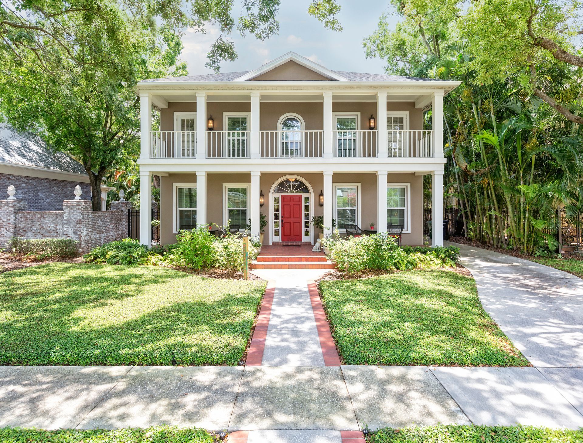 A large house with a red door and a brick walkway leading to it.
